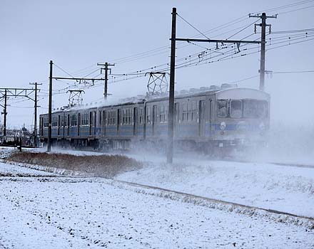 厳寒の中雪煙を上げて学生を輸送する弘南鉄道7000系４両編成